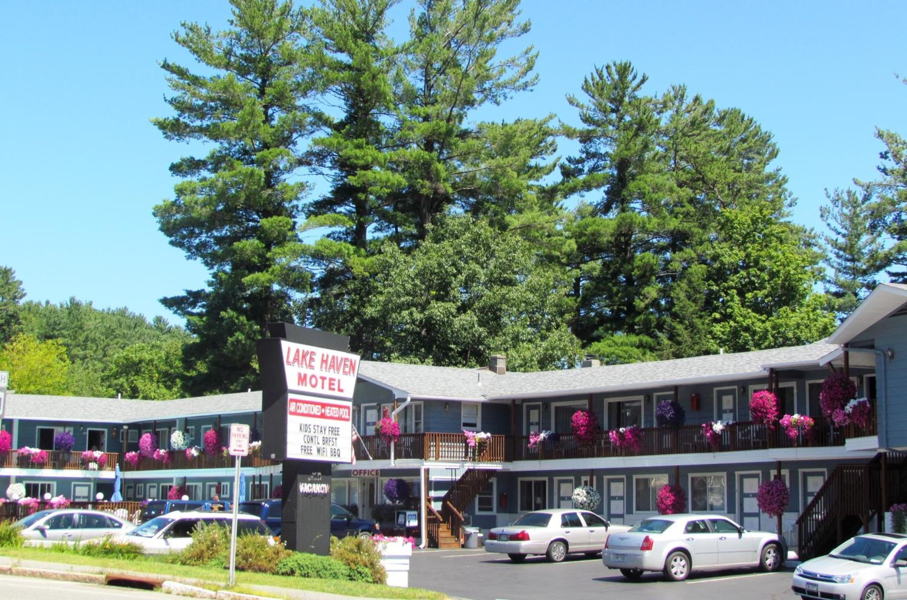 A two-story motel with a signboard, parking area, and cars.