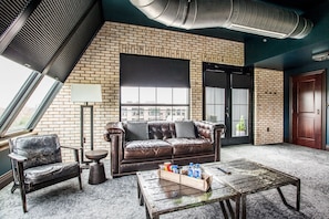 A room with a leather sofa, a wooden coffee table, and a brick wall.