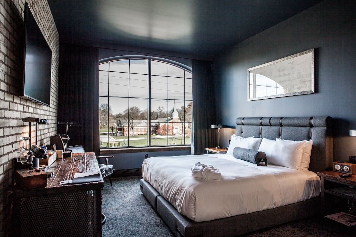 Ein modernes Hotelzimmer mit einem großen Bett, einem Schreibtisch und Blick ins Freie.