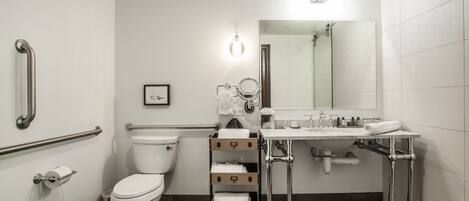 Un baño moderno con inodoro, lavamanos, espejo y carrito de almacenamiento.
