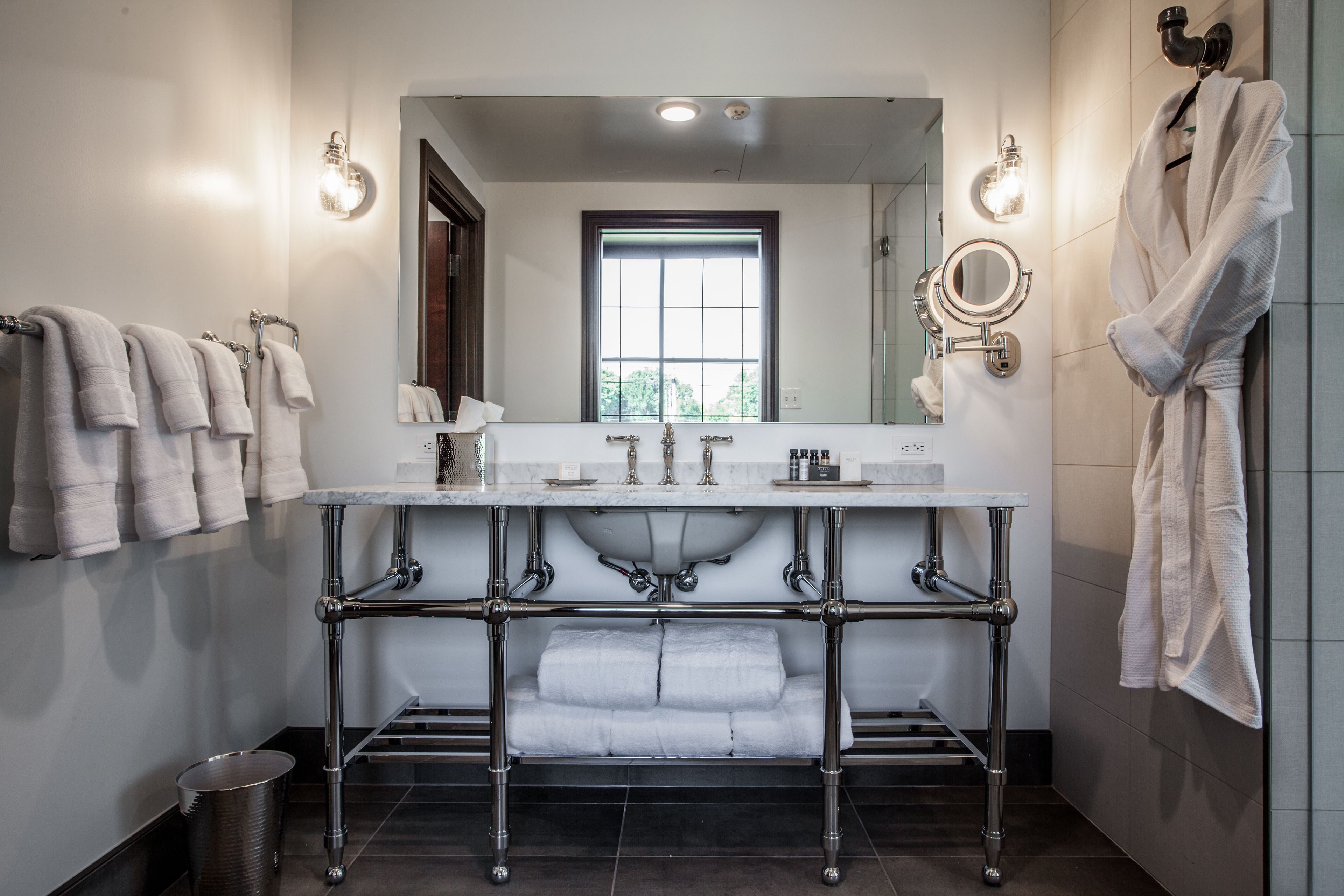 Une salle de bain moderne avec un grand miroir, deux lavabos et un porte-serviettes.