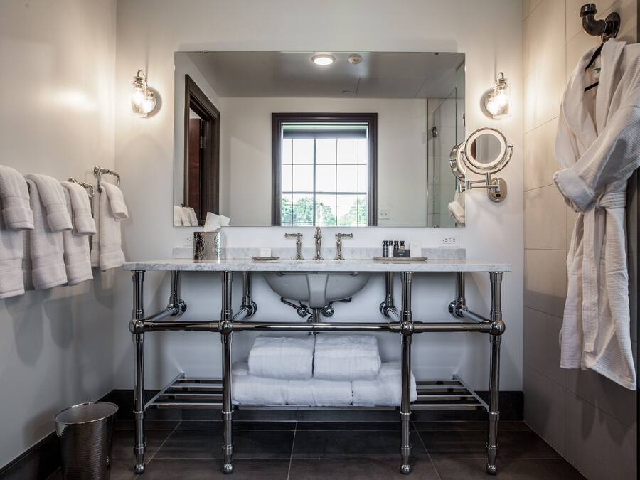 Une salle de bain moderne avec un grand miroir, deux lavabos et un porte-serviettes.