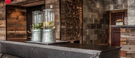 A bar area with a metal counter, a cushioned bench, and a wall with a textured pattern.