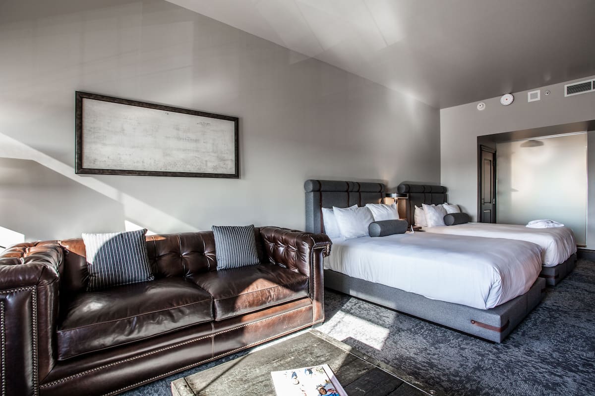 Ein modernes Hotelzimmer mit einer Ledersofa, einem großen Bett und einem gerahmten Bild an der Wand.
