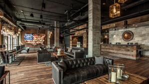 A spacious lounge area with leather sofas, wooden flooring, and a large American flag mural. - Ironworks Hotel Indy (Indianapolis)