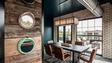 A modern dining area with a brick wall, large windows, and a round table with leather chairs.