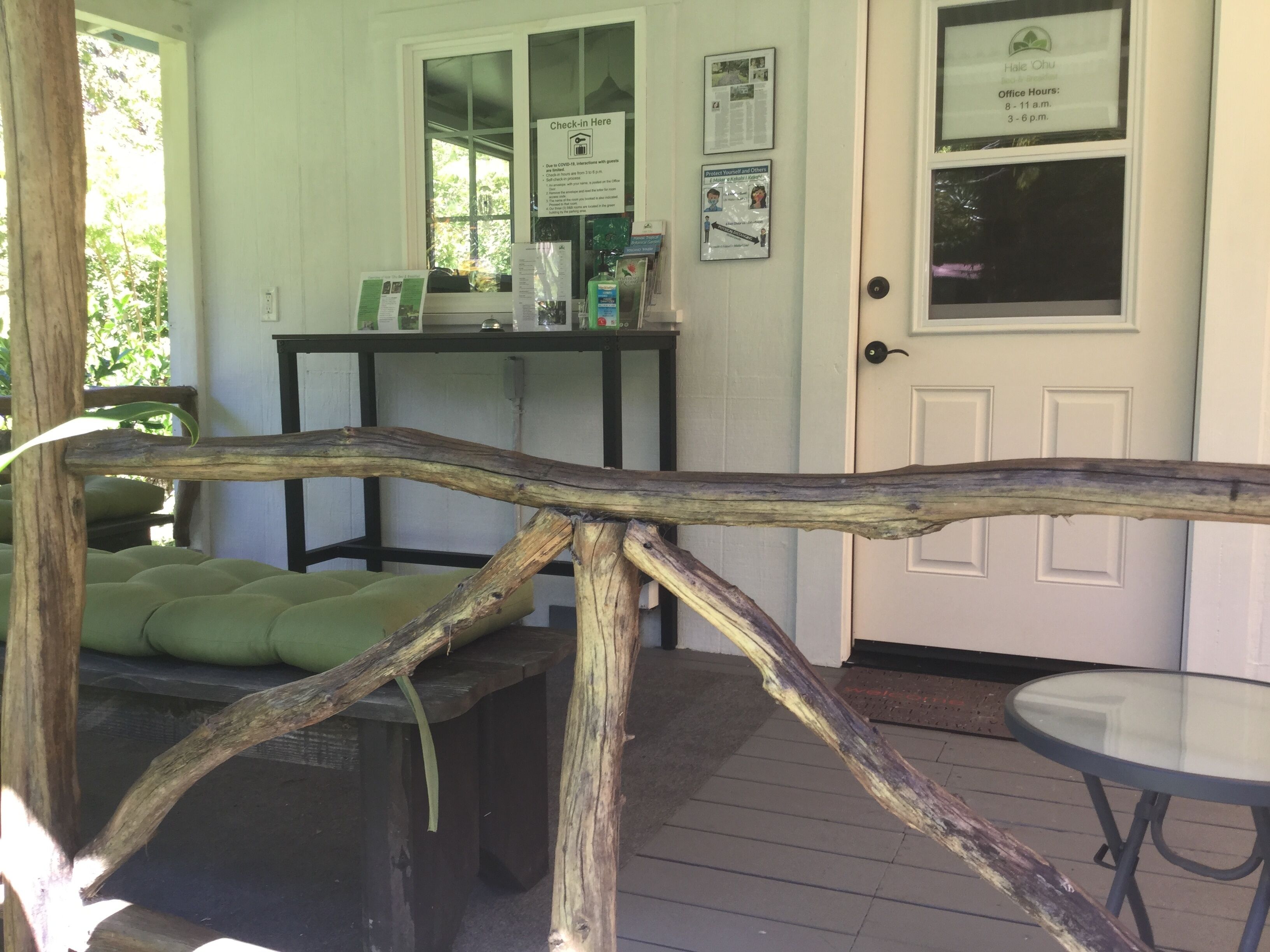 A reception area with a wooden barrier, a check-in desk, and a door with office hours posted.