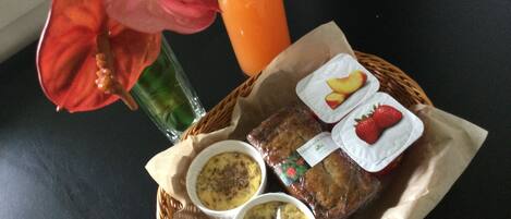 Eine Mahlzeit mit einer Orangensaftflasche, zwei Essensbehältern und einer roten Blume.