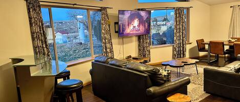 Una sala de estar moderna con chimenea, ventanas amplias, televisor y comedor.