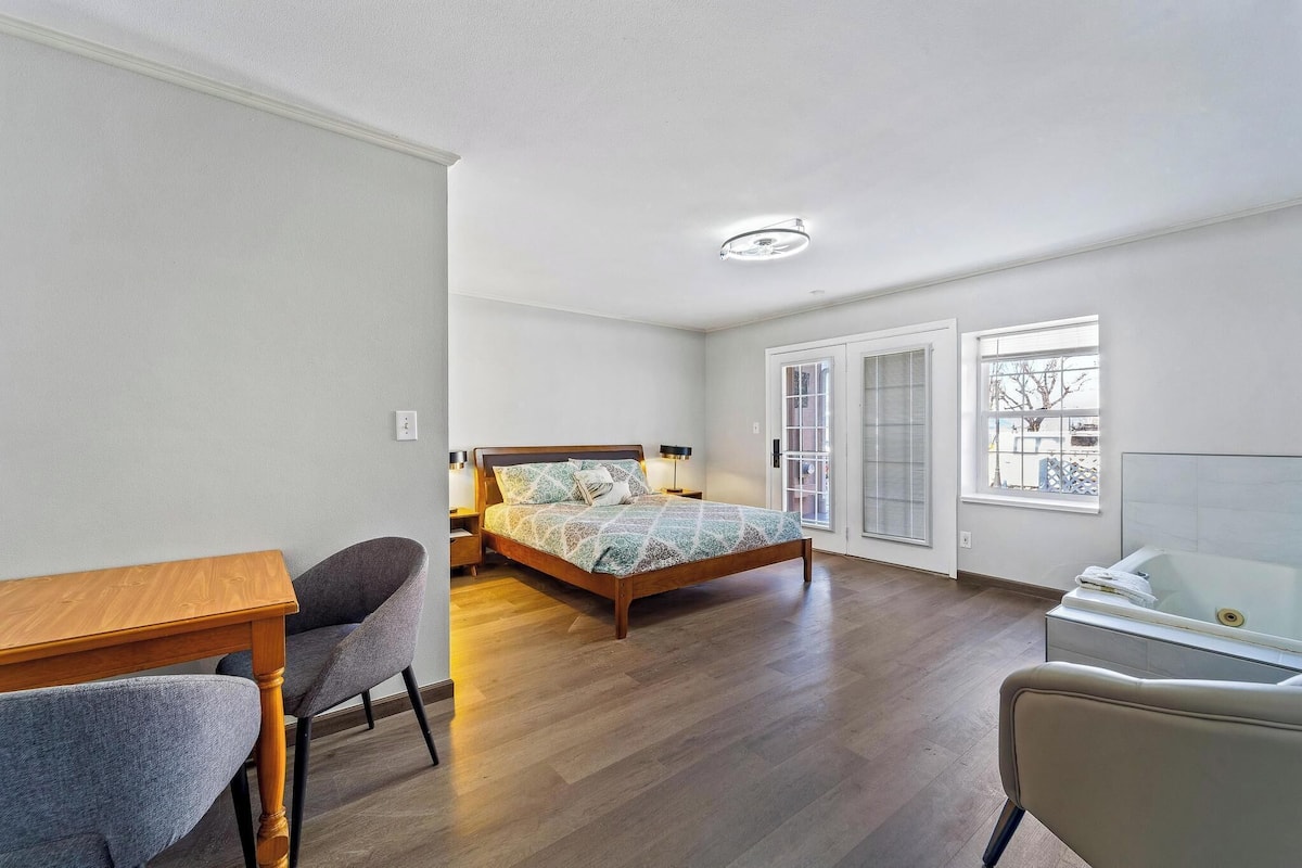 Ein Schlafzimmer mit einem hölzernen Bett, einem Schreibtisch, einem Stuhl, einem Fenster und einer Badewanne.