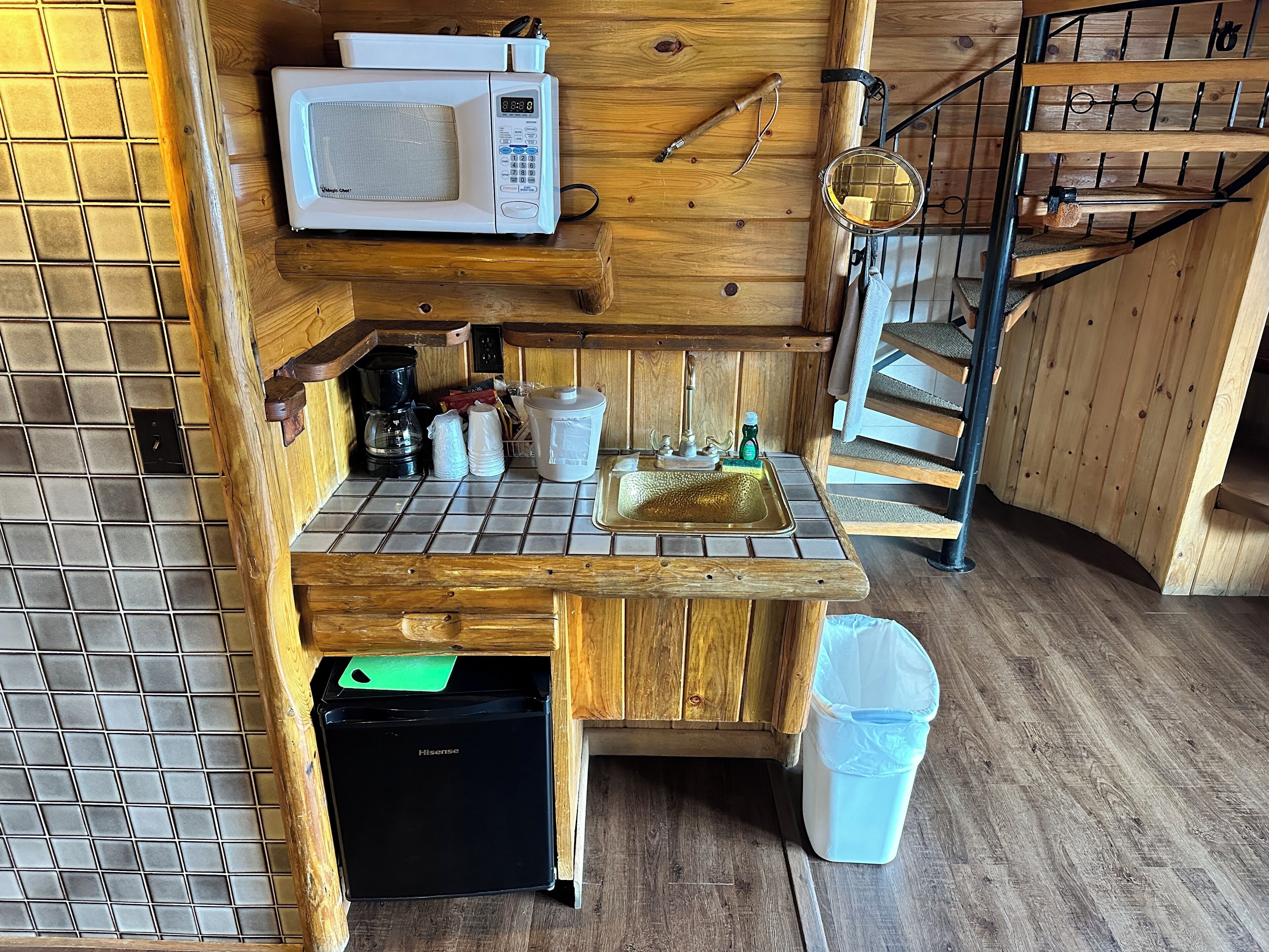 Een compacte keuken met een magnetron, spoelbak en een Hisense minibar.