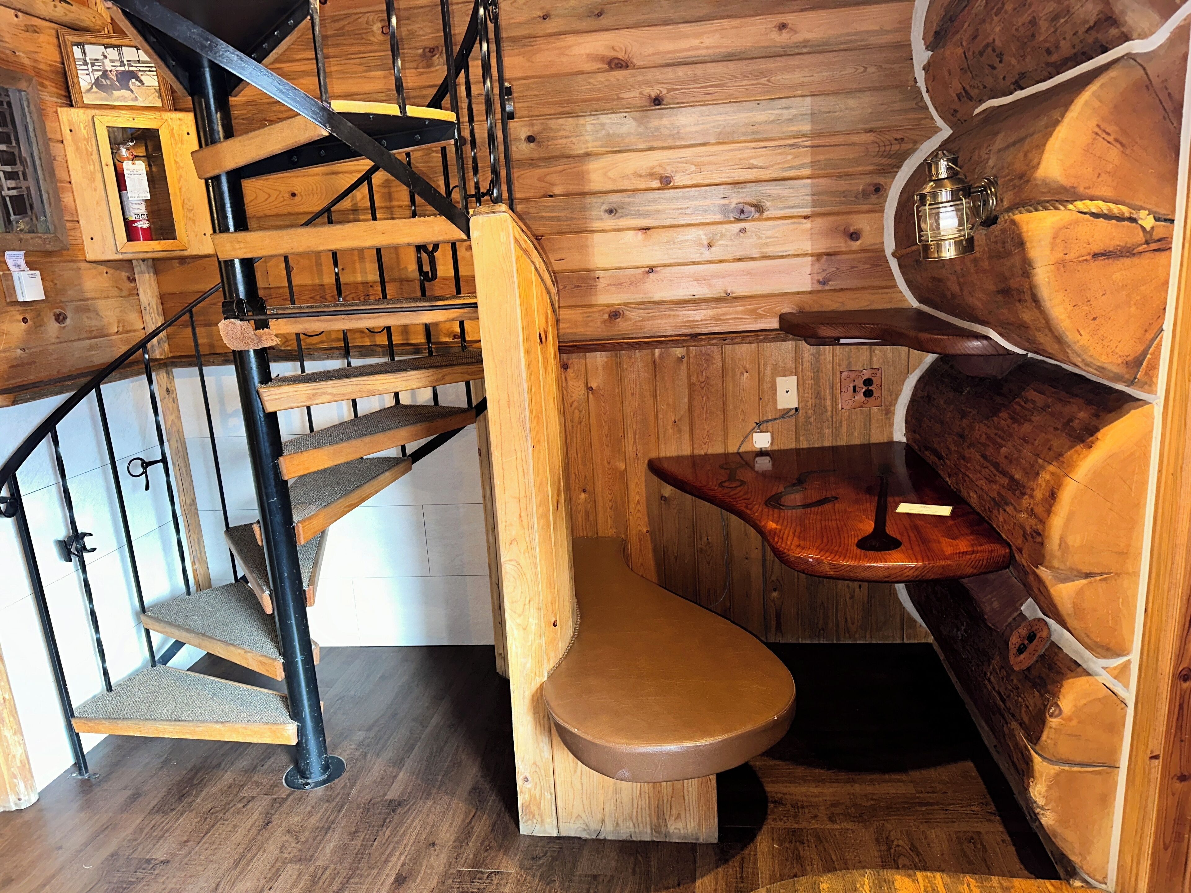 Un intérieur en bois avec un escalier en colimaçon, un banc en bois et un mur en bois intégrant une poutre.