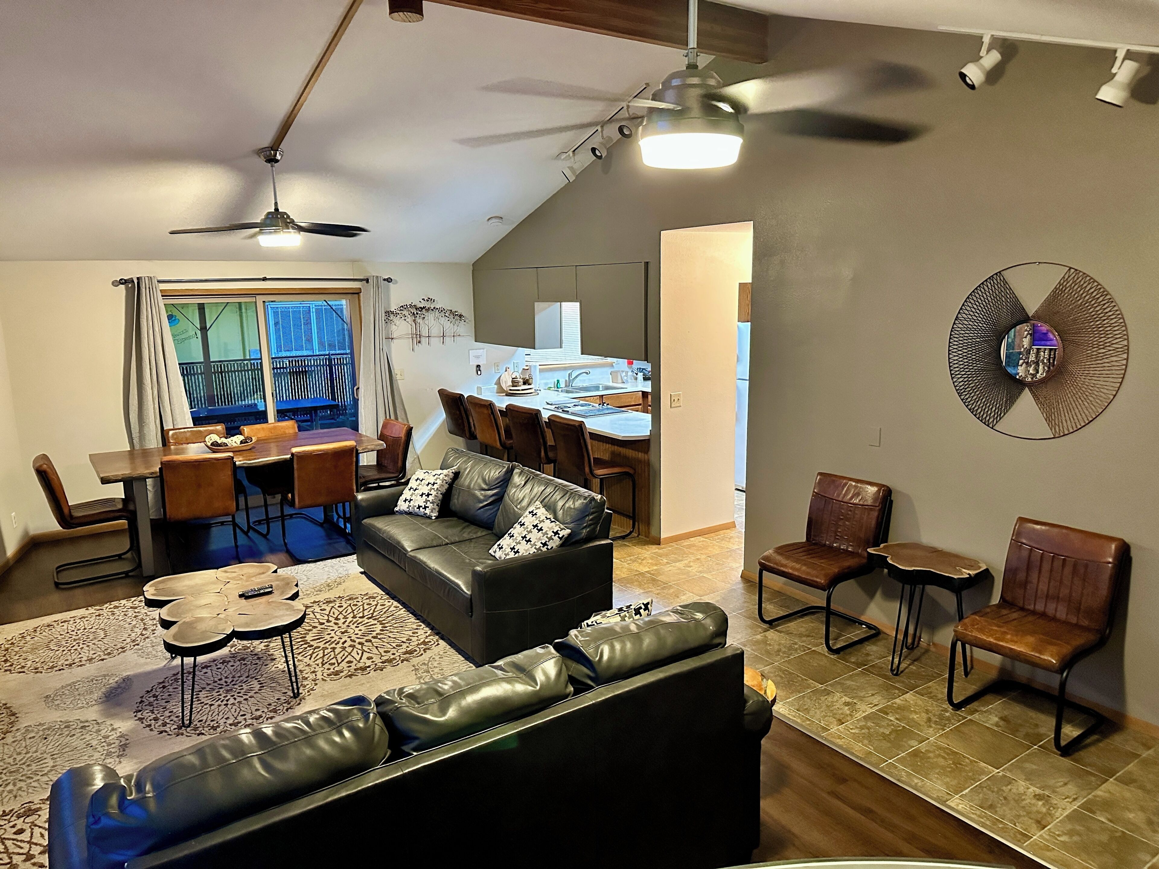 A modern living room with a leather sofa, dining area, and kitchen.
