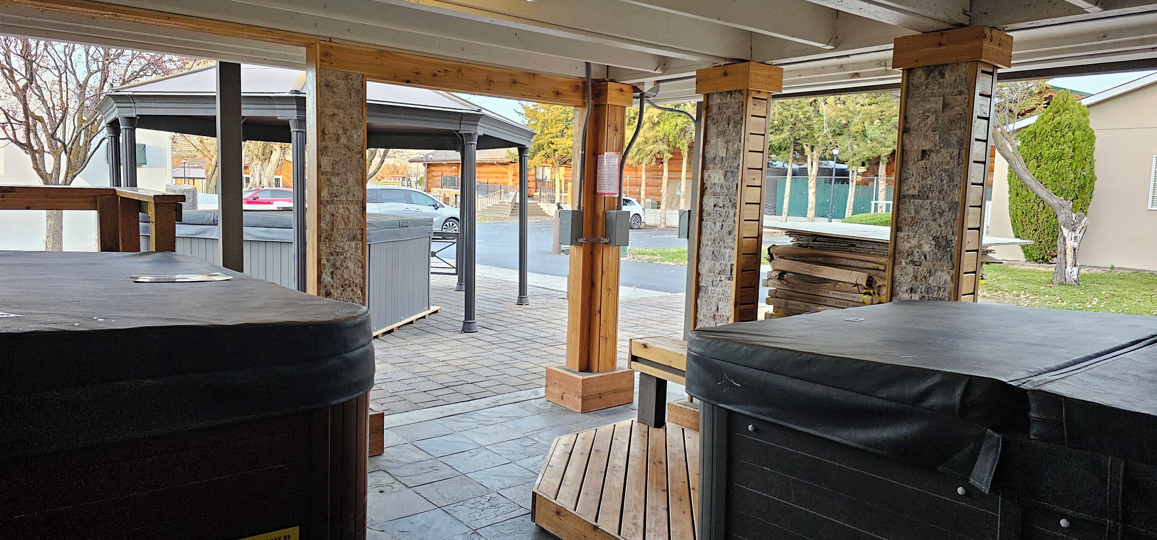 Un espace extérieur aménagé en terrasse, avec deux bains à remous, un coin salon couvert et une vue sur la rue.