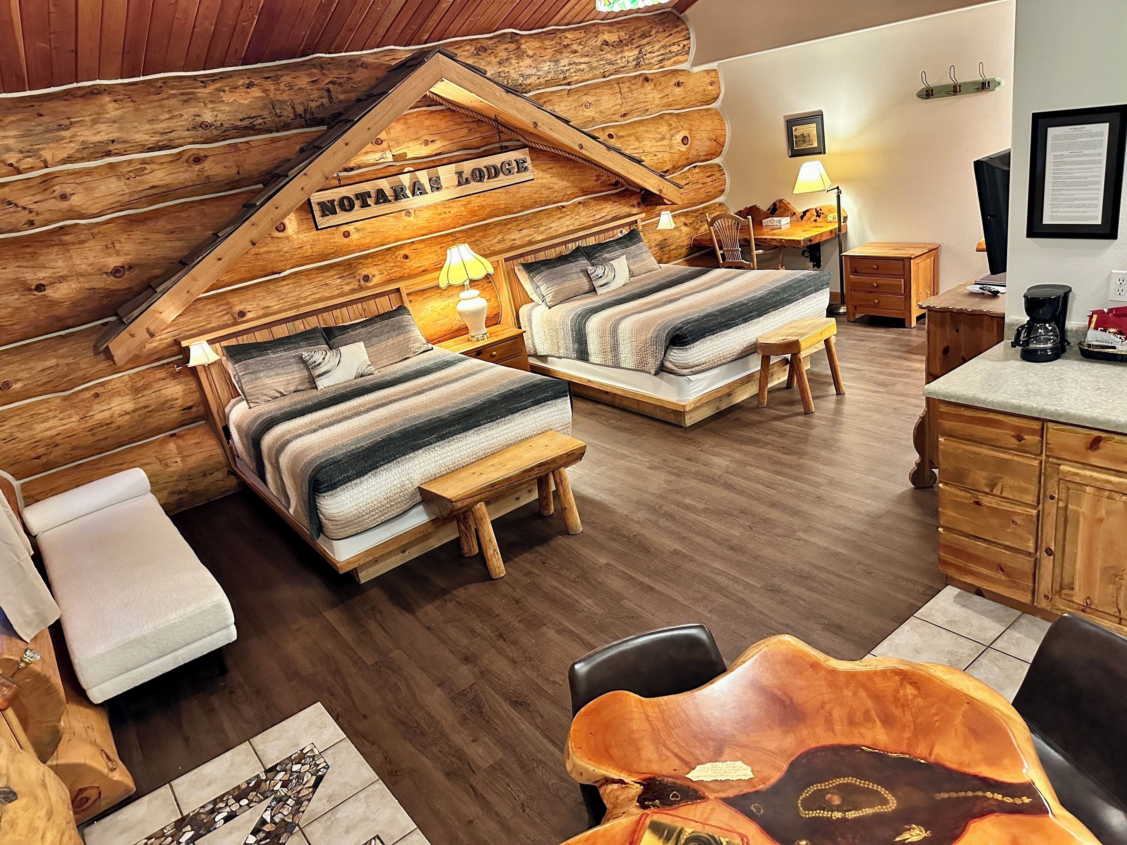 A cozy log cabin-style room with two beds, wooden furniture, and a rustic aesthetic.