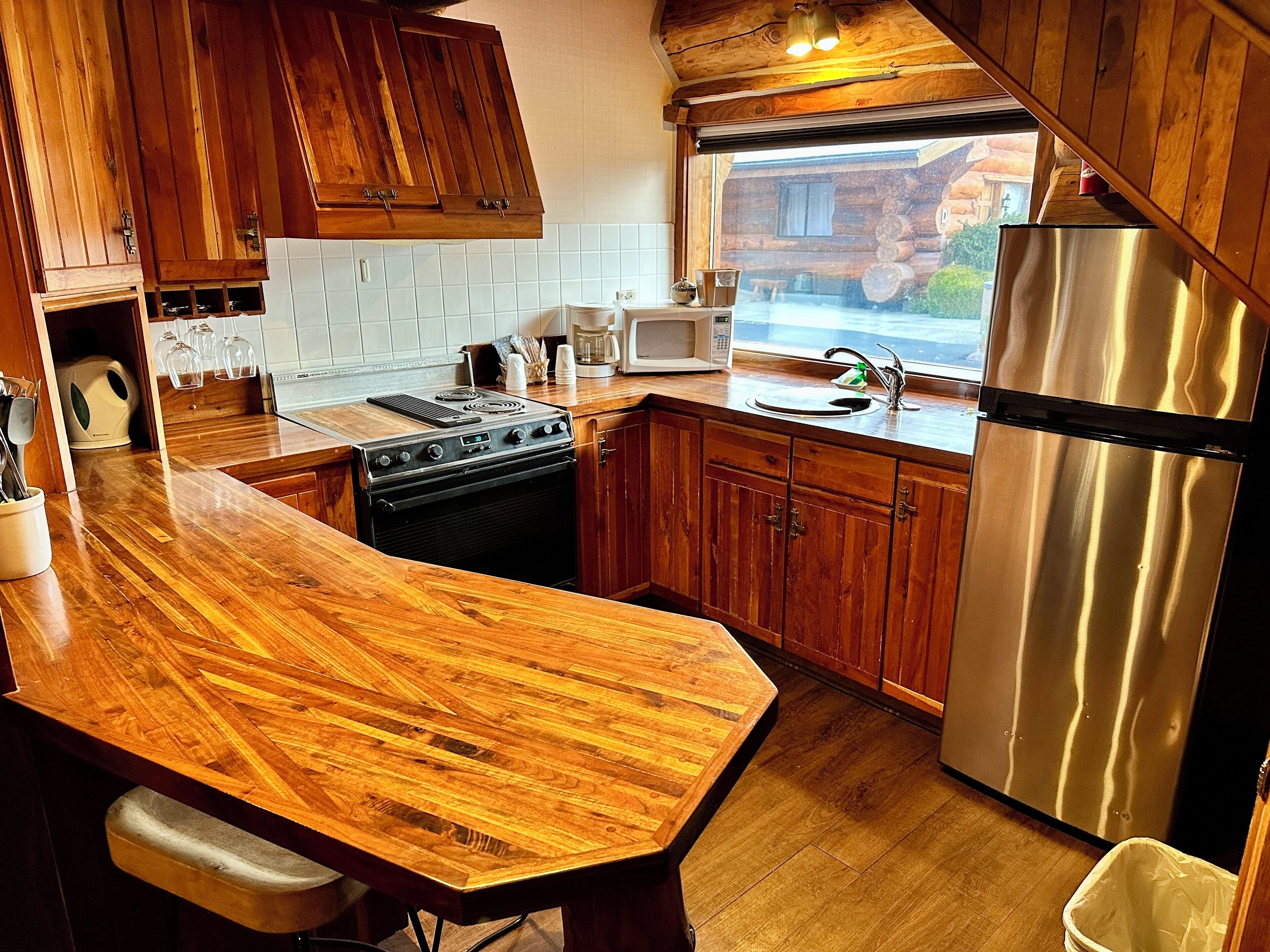 A kitchen with wooden cabinets, a stainless steel refrigerator, a microwave, and a stove.