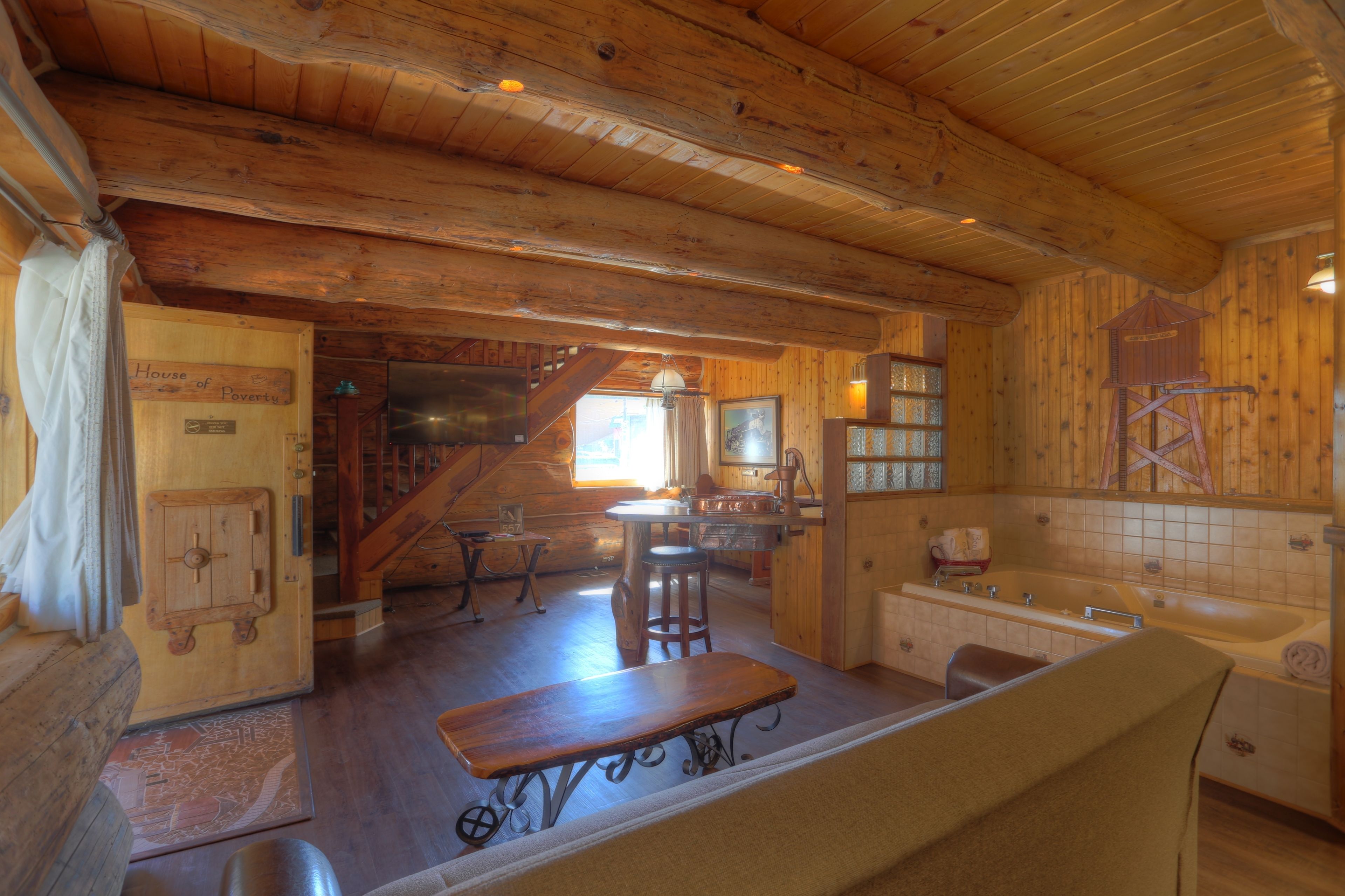A rustic wooden interior with a dining area, kitchen, and a large bathtub.
