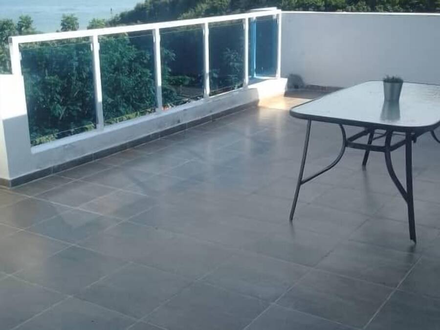 A rooftop terrace with a glass balustrade, a table, and chairs.