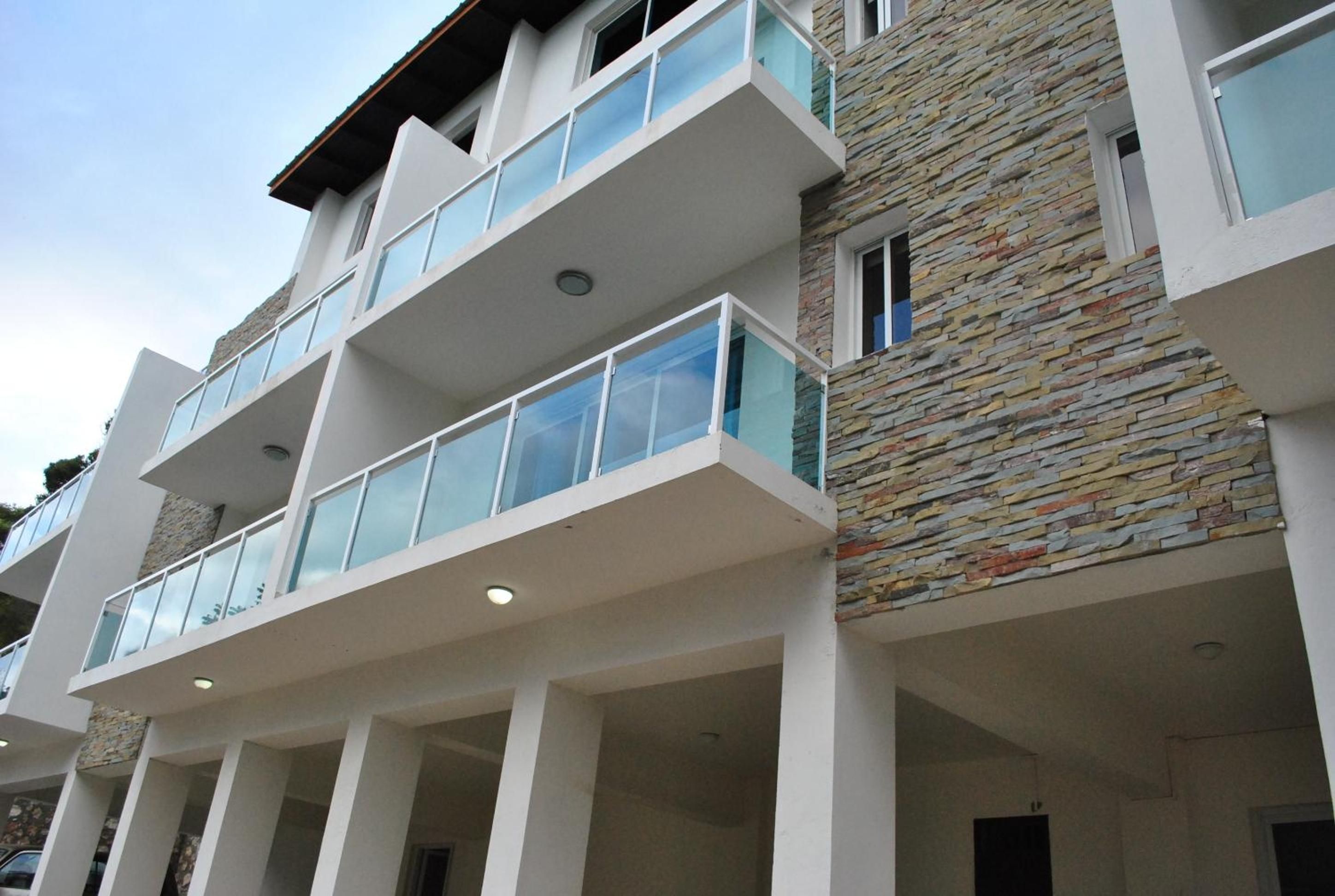 A multi-story building with a modern architectural design, featuring balconies with glass railings and a stone facade.