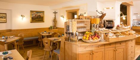 Un restaurante acogedor con muebles de madera, una zona de bar central con fruteros y luces fijadas en la pared.