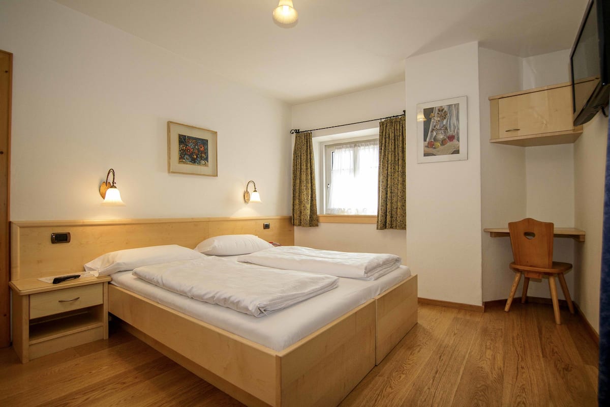 Ein Schlafzimmer mit einem Holzbett, Nachttischen, einem Schreibtisch und einem Stuhl.