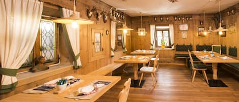 A restaurant with wooden tables and benches, a wooden floor, and a rustic decor with animal skulls on the walls.