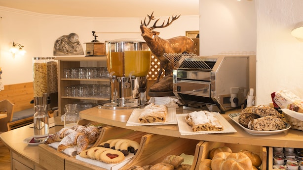 A buffet counter with various baked goods, pastries, and beverages.