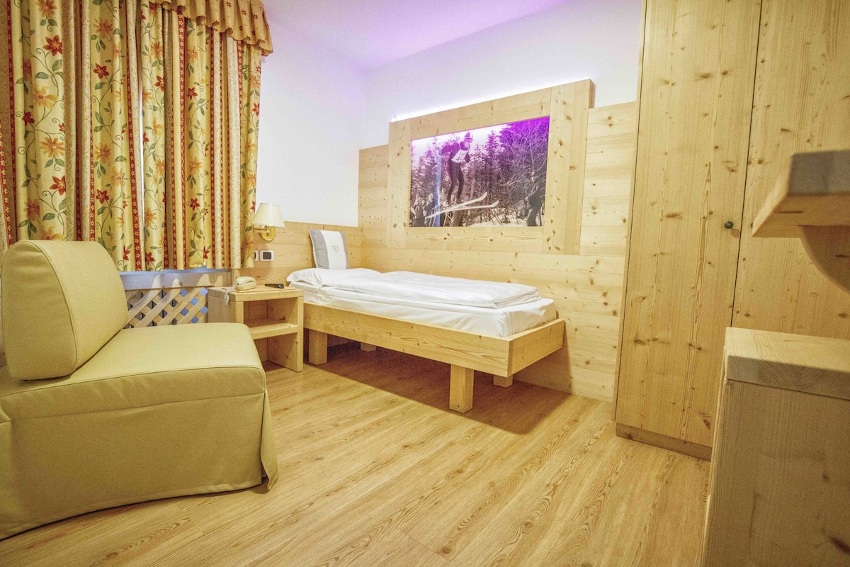 Ein Zimmer mit Holzboden, einem Bett, einem Schlafsofa und einem Nachttisch.