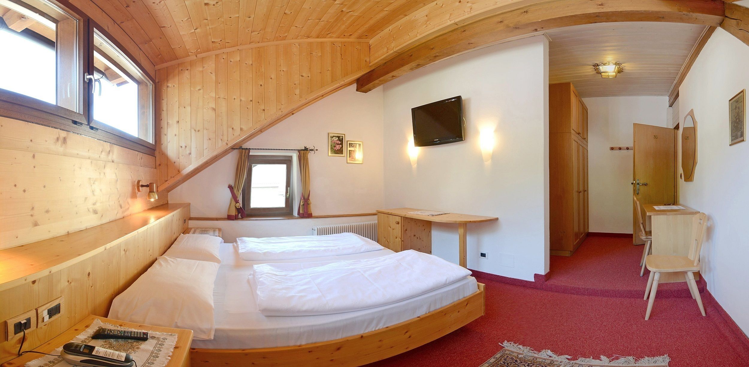 Una habitación con dos camas, televisión y un escritorio pequeño.