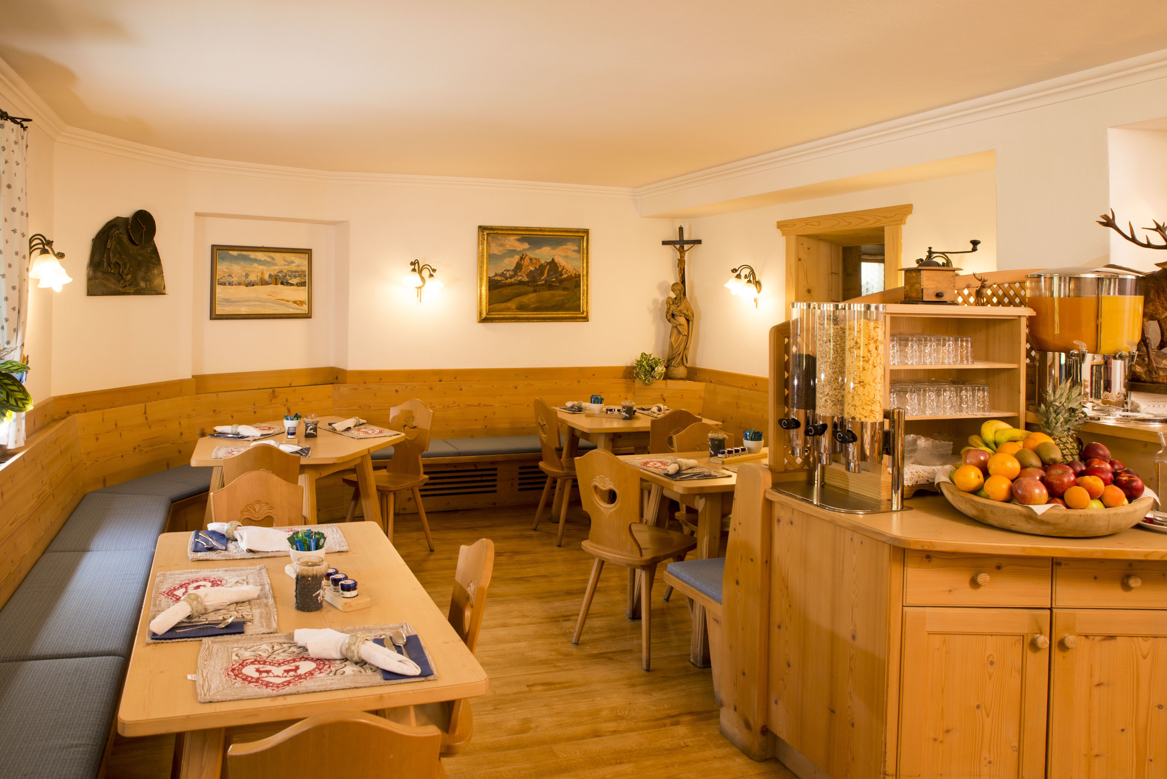 Ein gemütliches Restaurant mit Holzkubaturen, einer Auswahl an Früchten auf der Theke und religiösen Kunstwerken an den Wänden.