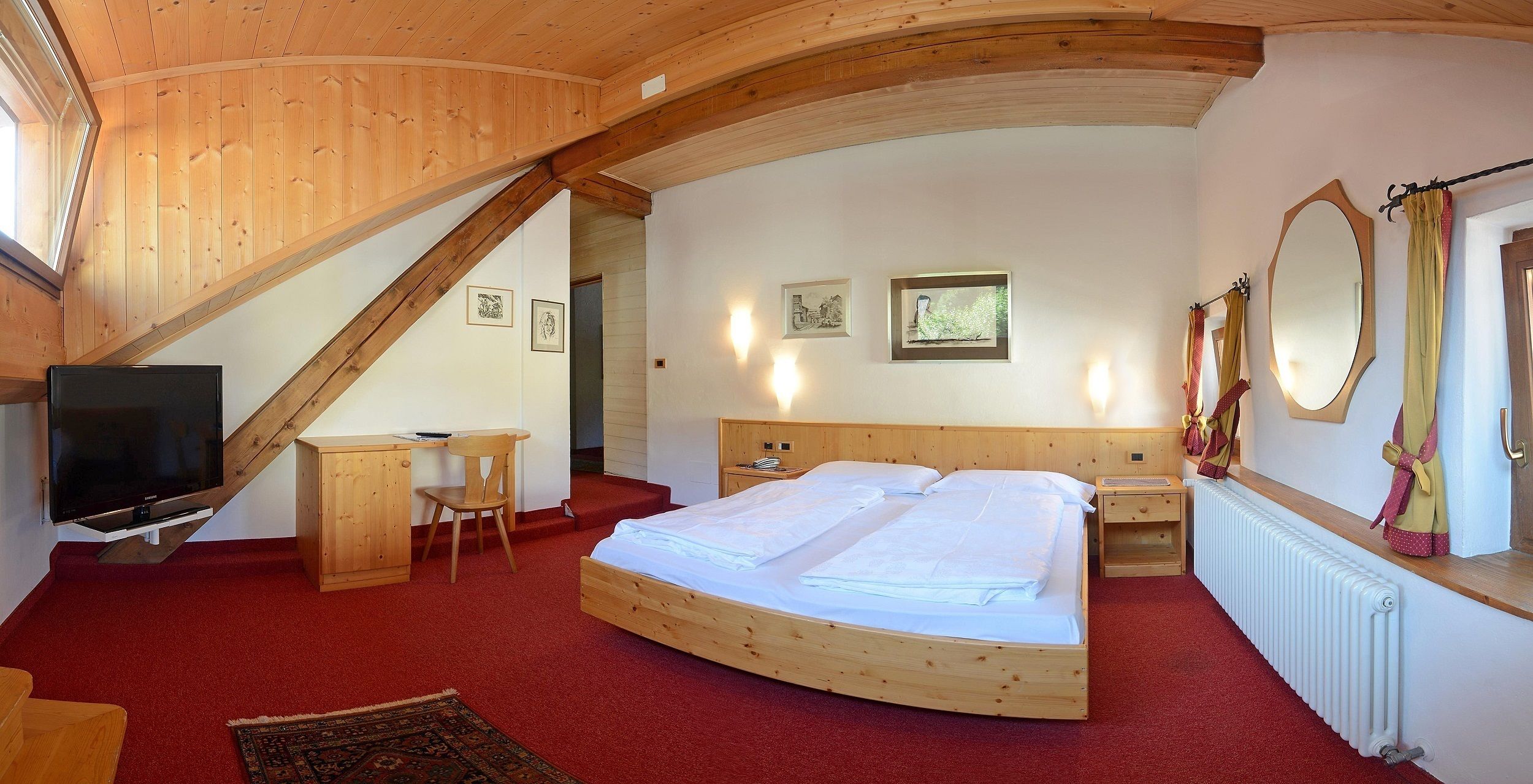 Une chambre à coucher avec un lit en bois, un bureau, une chaise, une télévision et un grand miroir.