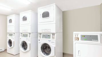 A row of stacked front-loading washing machines in a laundry room.