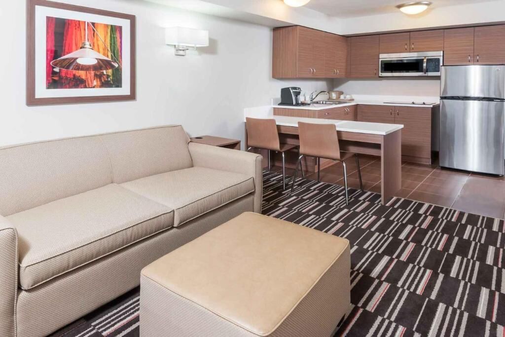 A modern living room with a sofa, ottoman, and a dining area with chairs and a table.