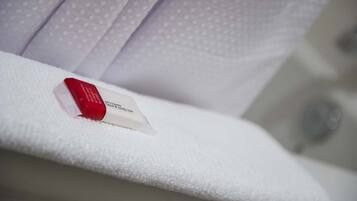 A white towel with a red object on it, possibly a bar of soap, in a bathroom setting.
