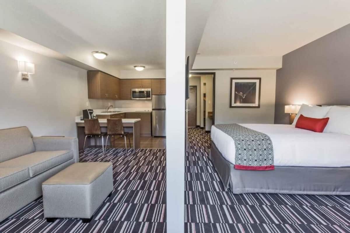 Ein Hotelzimmer mit Bett, einer Couch, einem kleinen Tisch und einer Küchenzeile.