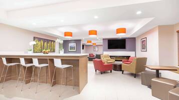 A modern living room with a bar area, seating, and a flat-screen TV.