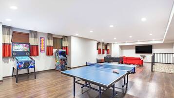 Relax and play in this spacious indoor recreation area, featuring a ping pong table, arcade games, and a modern video game console.