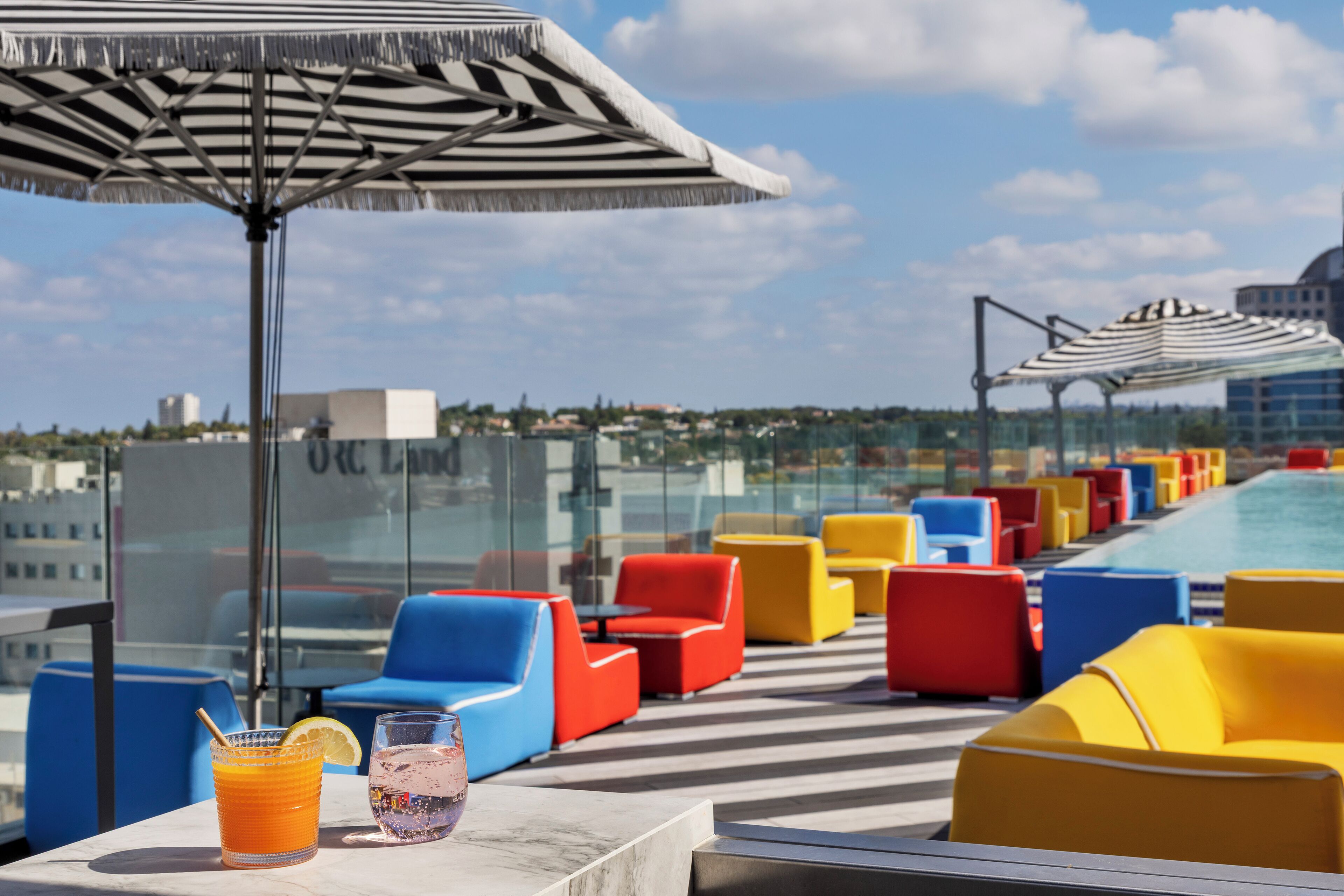 A rooftop bar with colorful seating and a pool view.