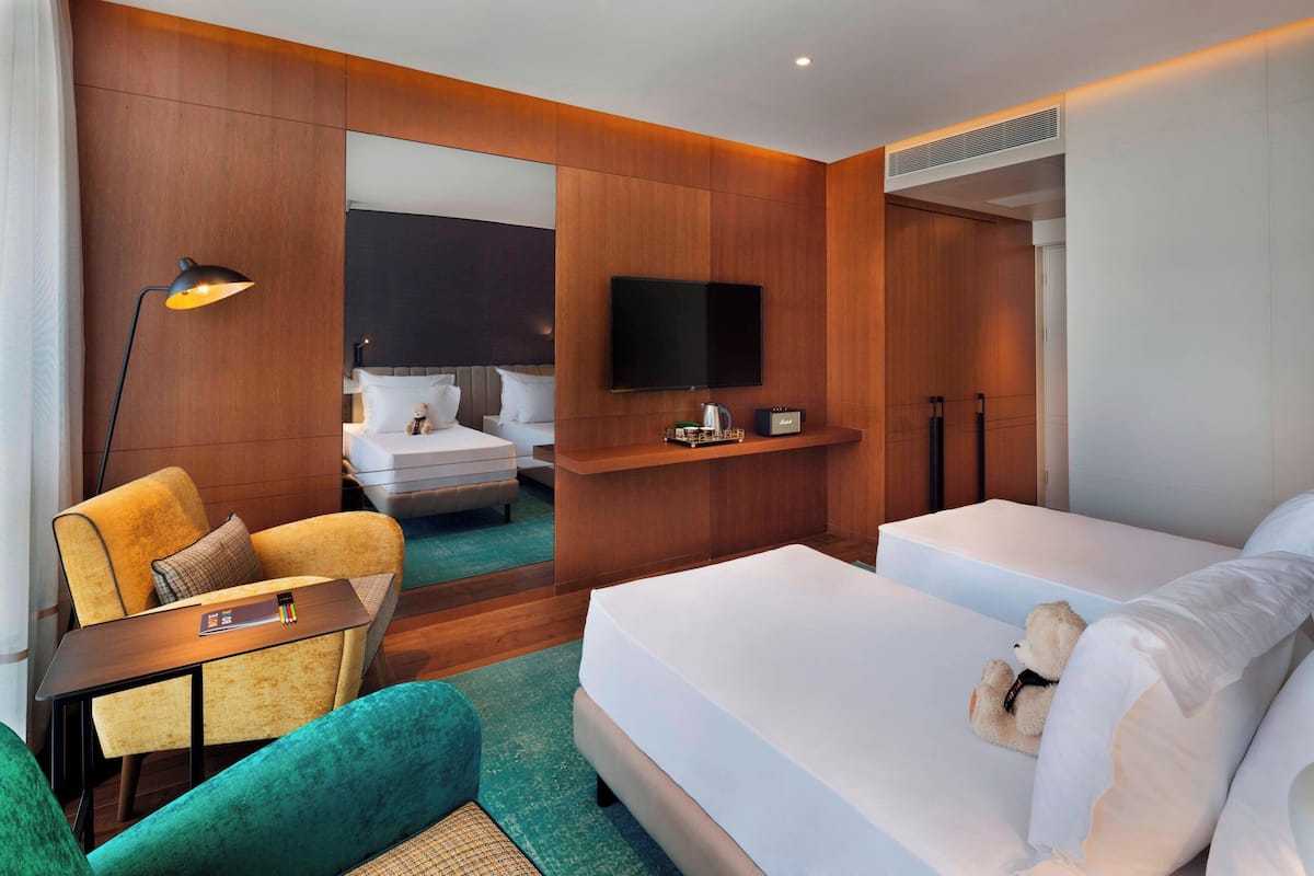 A hotel room with a bed, a chair, a desk, a TV, and a mirror.