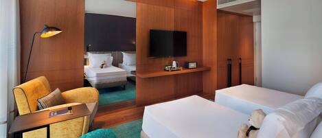 Habitación de hotel con cama, una silla, escritorio, televisor y espejo.
