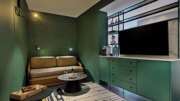 A modern living room with a sofa, a coffee table, and a kitchen area with a TV and cabinets.