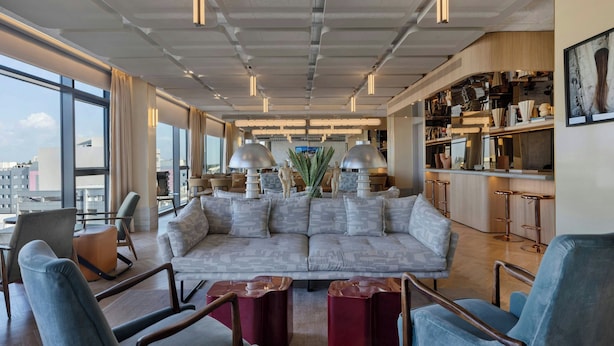 A modern living room with a sectional sofa, bar stools, and a kitchen area with bar seating.