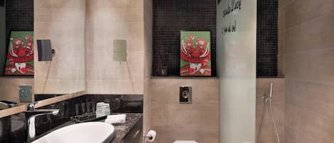 A modern bathroom with a large oval sink, a toilet, and a walk-in shower.