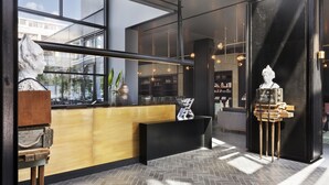 A modern reception area with a wooden counter, black reception desk, and a sculpture on a stand.
