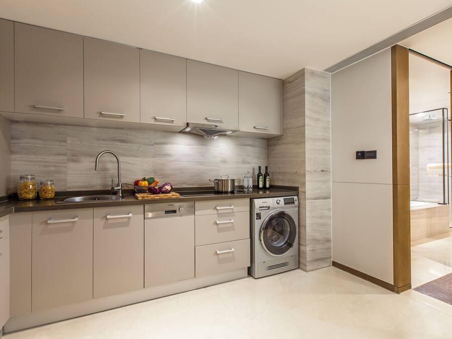 A modern kitchen with a built-in washing machine, stainless steel appliances, and a marble backsplash.