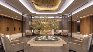 A lobby with a central tree, seating areas, and a modern ceiling design. - Ascott Riverside Garden Beijing (Beijing)