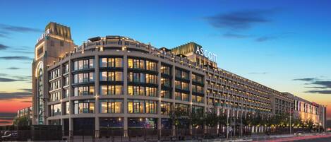 Un hôtel à plusieurs étages, reconnaissable à son grand panneau « ASCOTT », qui se distingue par son architecture moderne, sa façade incurvée et ses nombreux balcons.