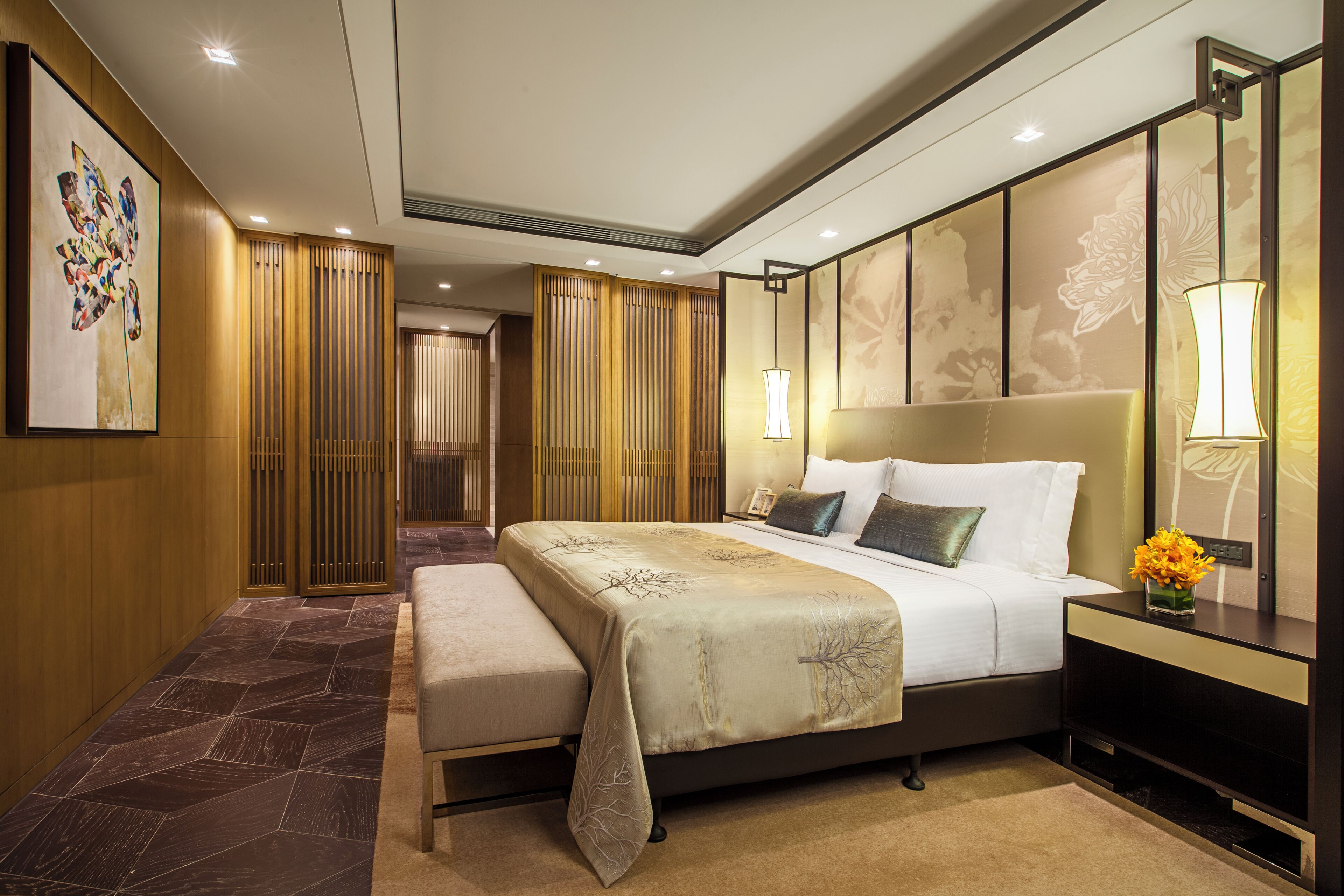Una habitación de hotel moderna con una cama grande, lámparas de noche, una mesita de noche y un panel decorativo en la pared.