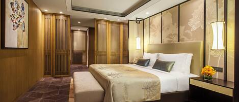 A modern hotel room with a large bed, bedside lamps, a nightstand, and a decorative wall panel.