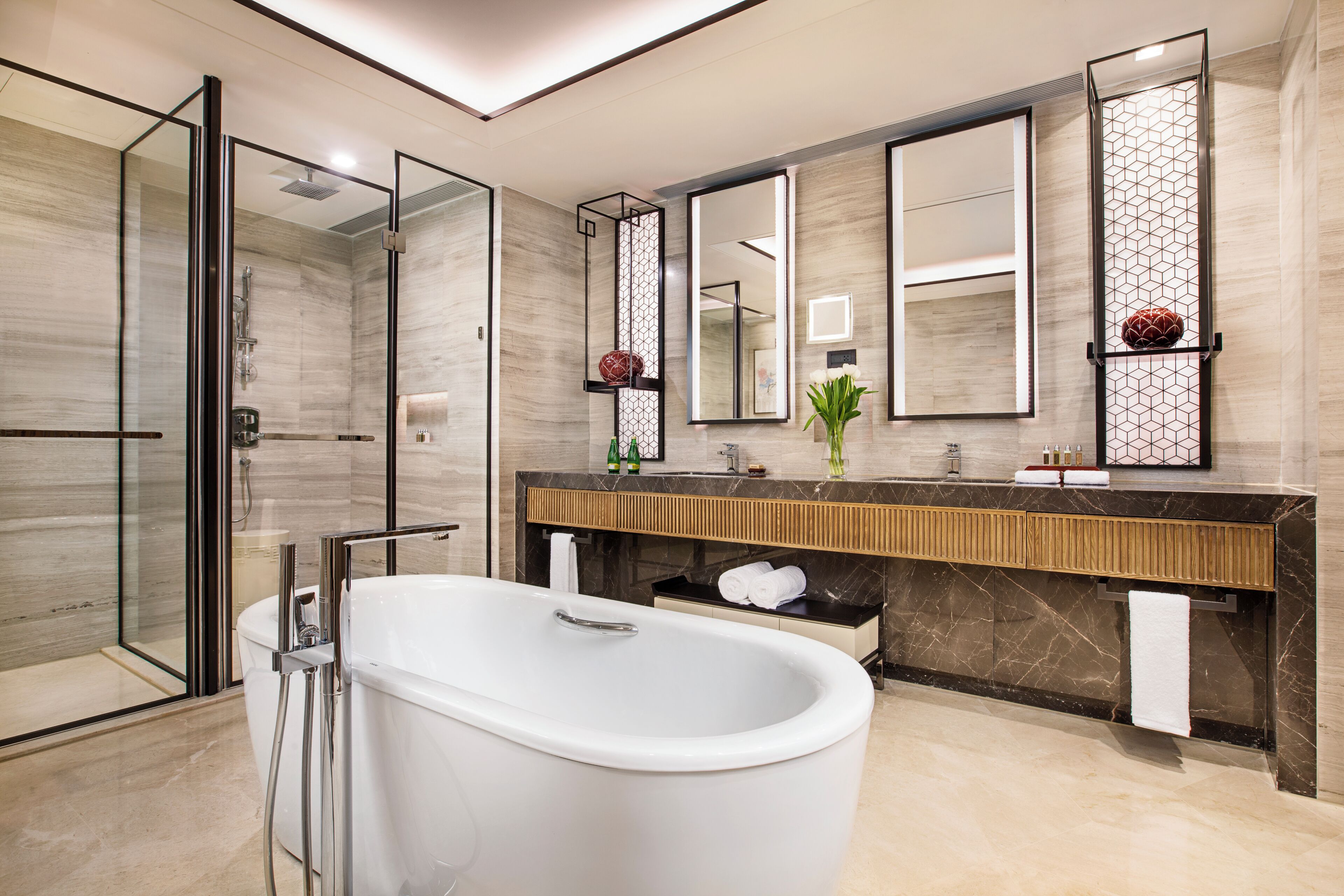 A modern bathroom with a glass-enclosed shower, a freestanding bathtub, and a vanity with a large mirror.